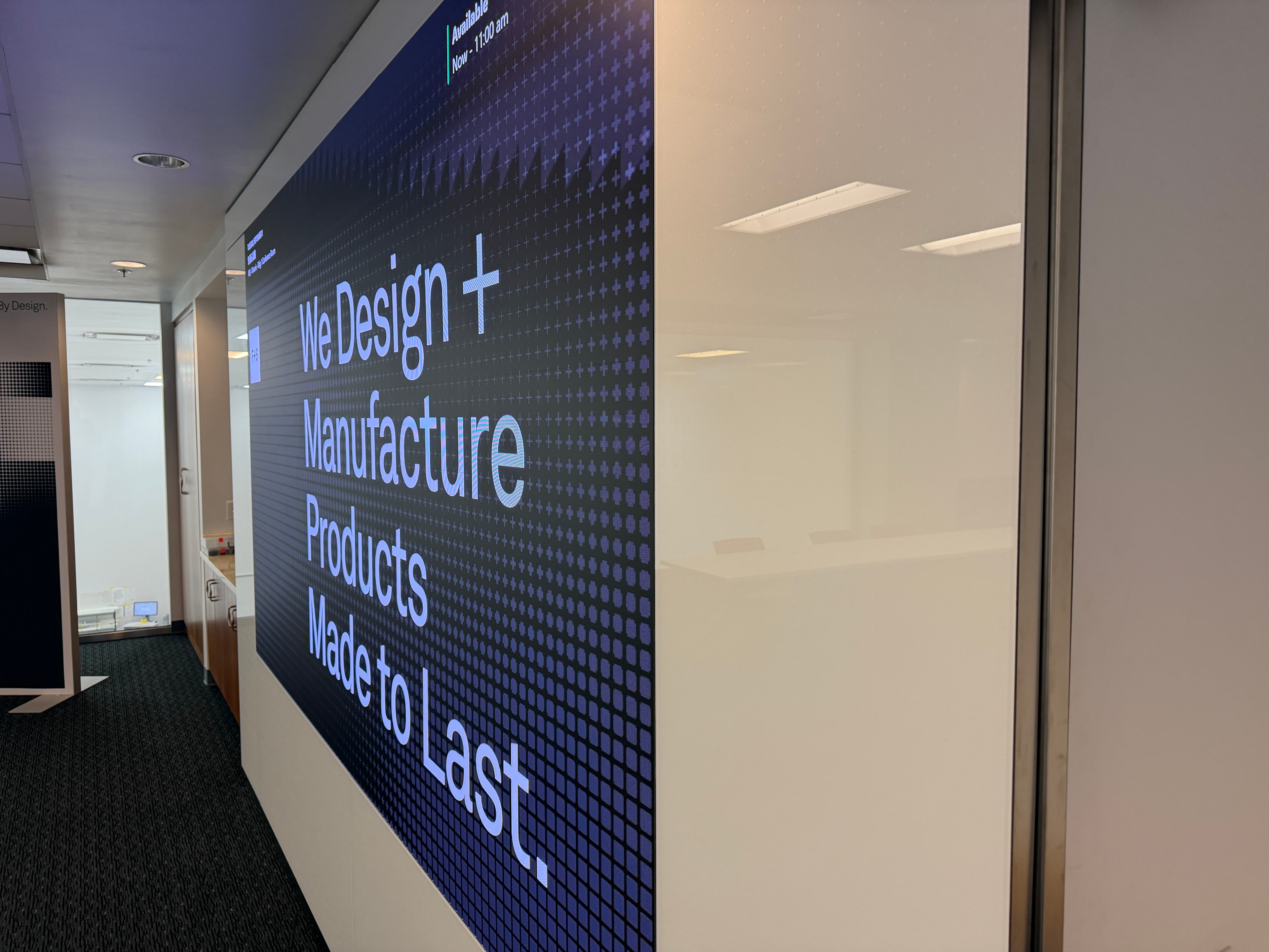 Side angle view of Forms + Surfaces LED display integrated with glass wall system